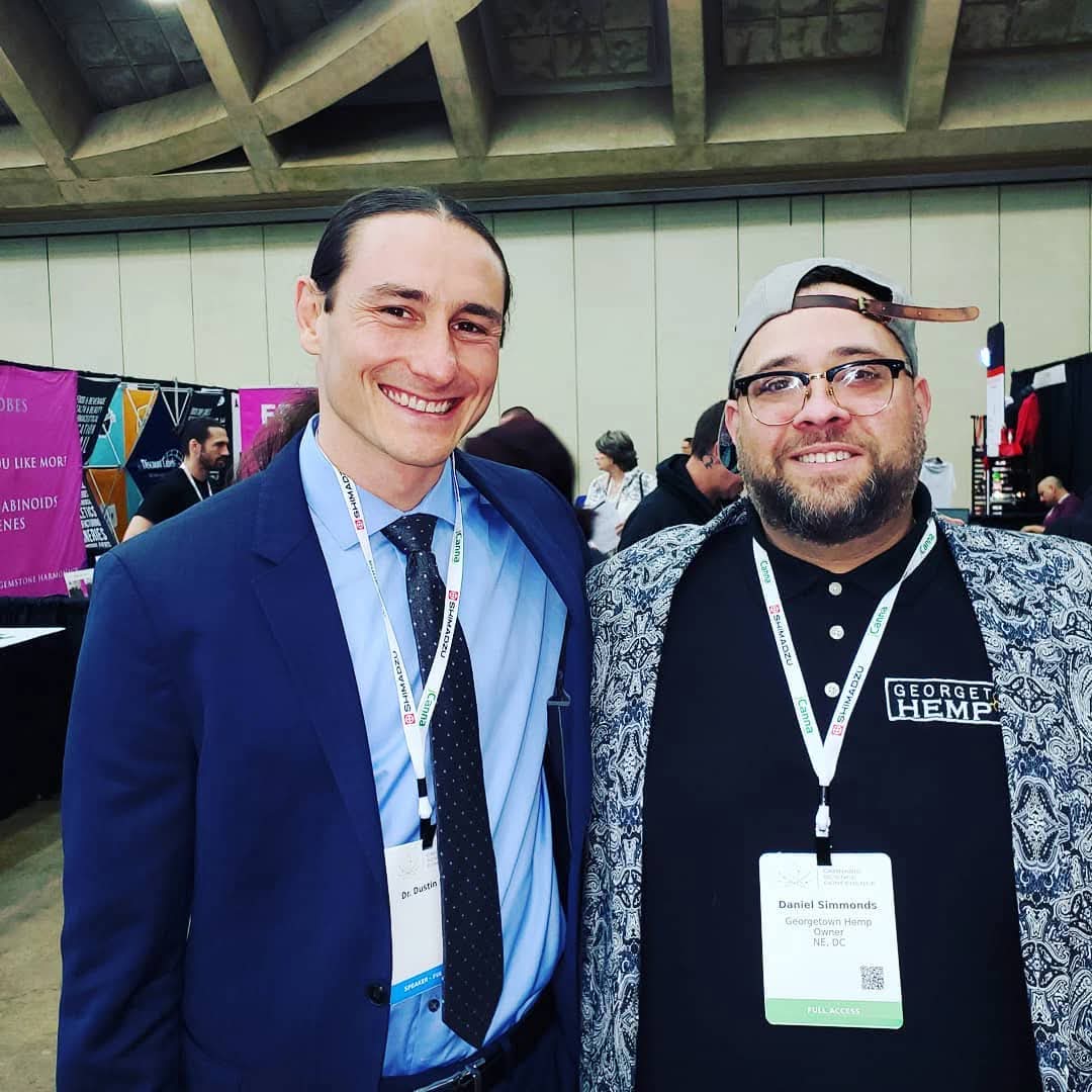Daniel Simmonds in Georgetown Hemp polo next to researcher at conference